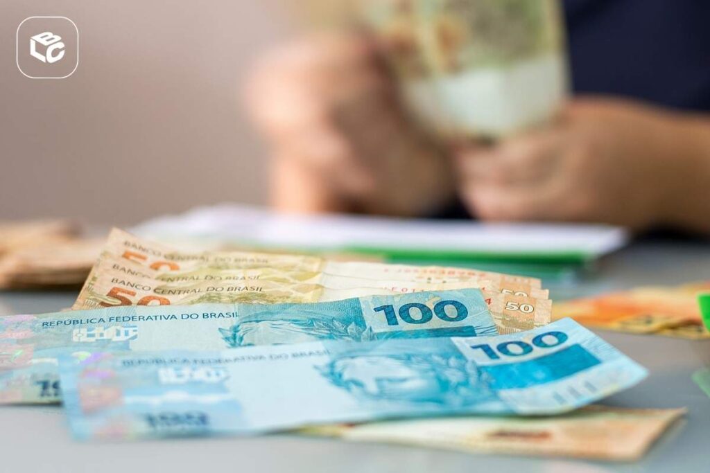 Imagem de uma mão contando cédulas de cinquenta reais e de cem reais